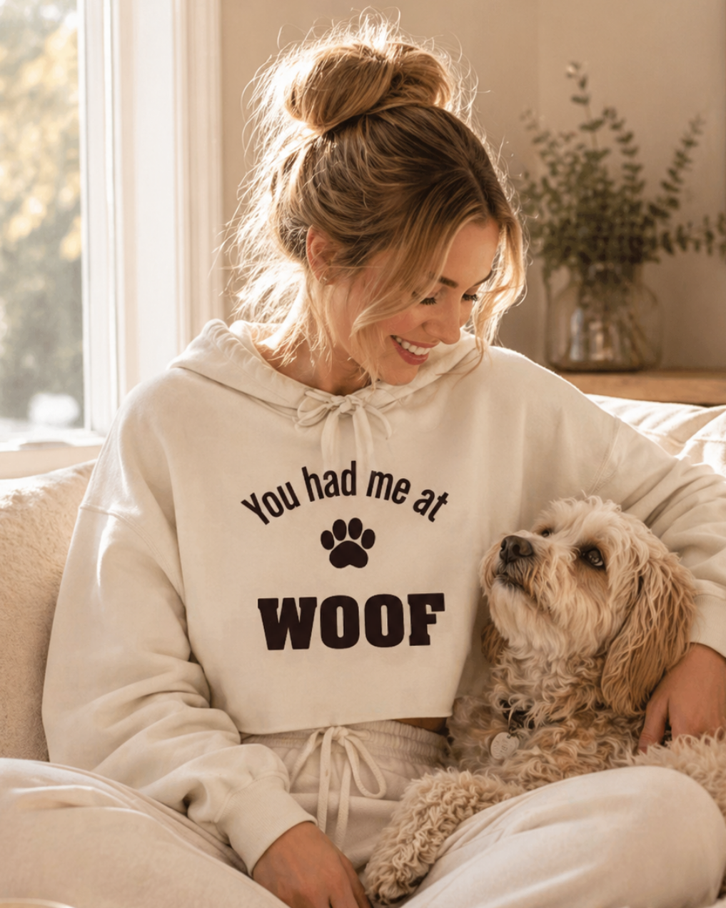 Woman wearing a hoodie with 'You had me at WOOF' text sitting on a couch with a dog.